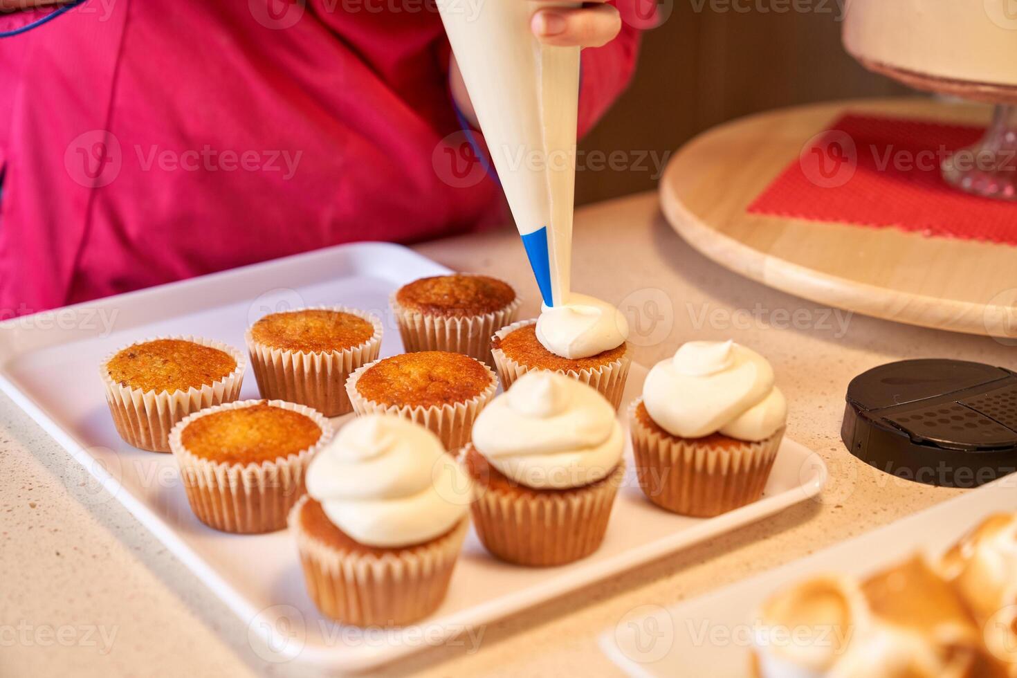 Crop confectioner icing cupcakes with buttercream photo