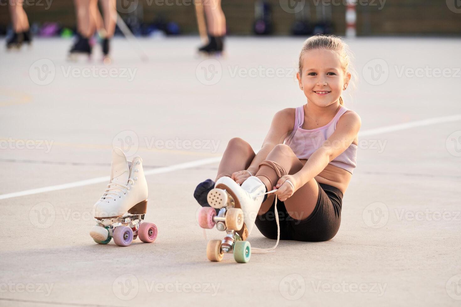 Cheerful child putting on roller skates in city photo