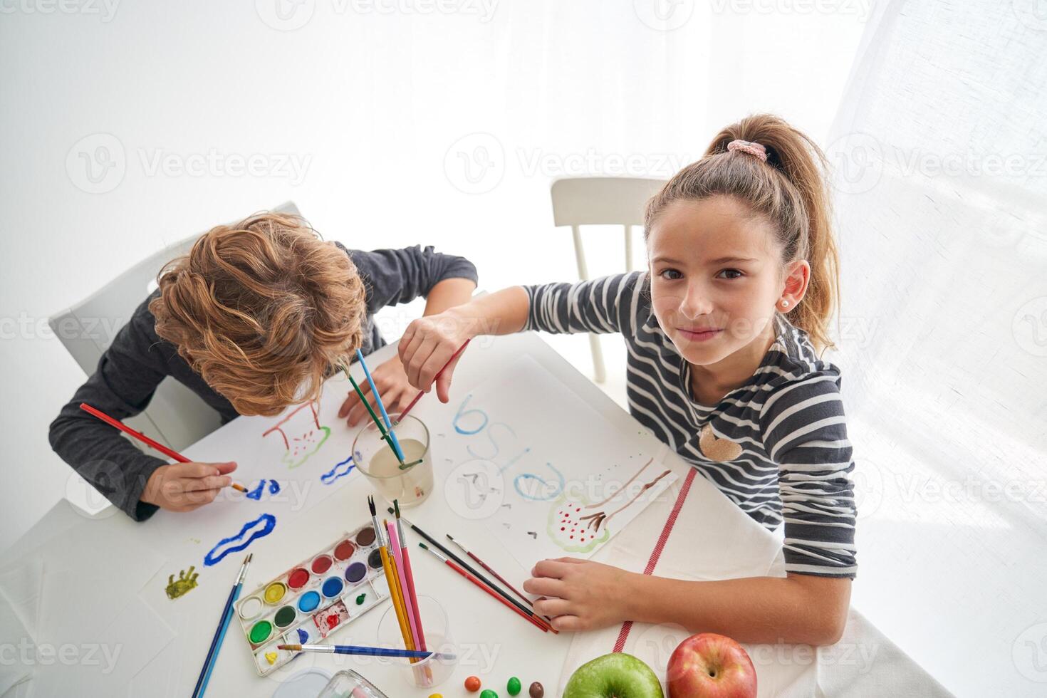 Positive girl painting near boy photo