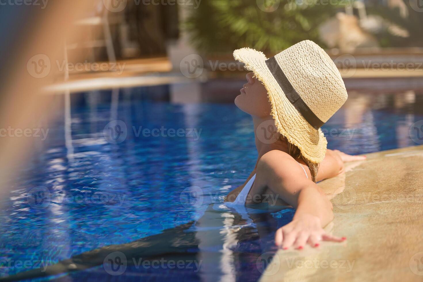 Anonymous female tourist resting in pool at resort photo