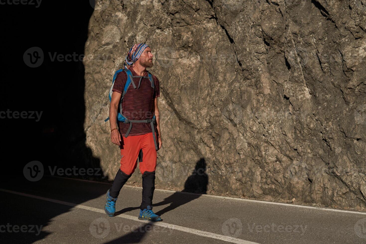 Traveling man walking on asphalt road near mountains photo