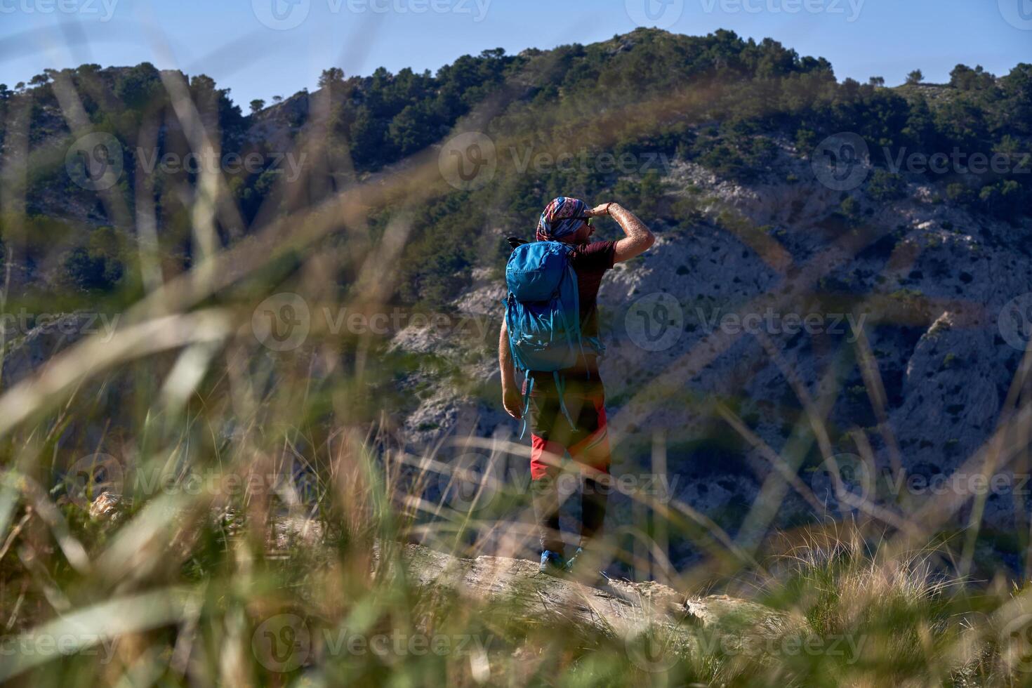 Backpacker shielding eyes on mountain photo