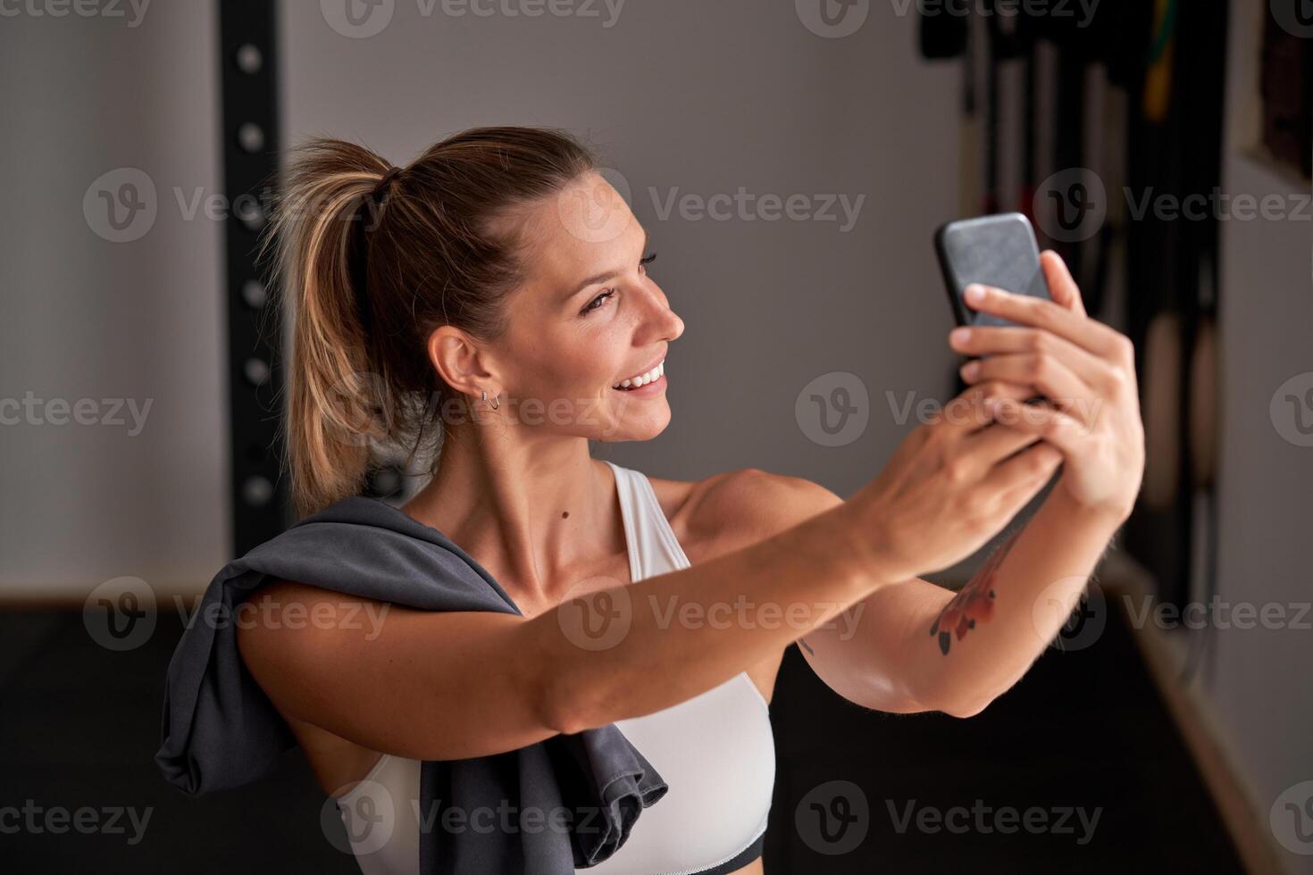 Smiling sportswoman taking selfie in gym photo