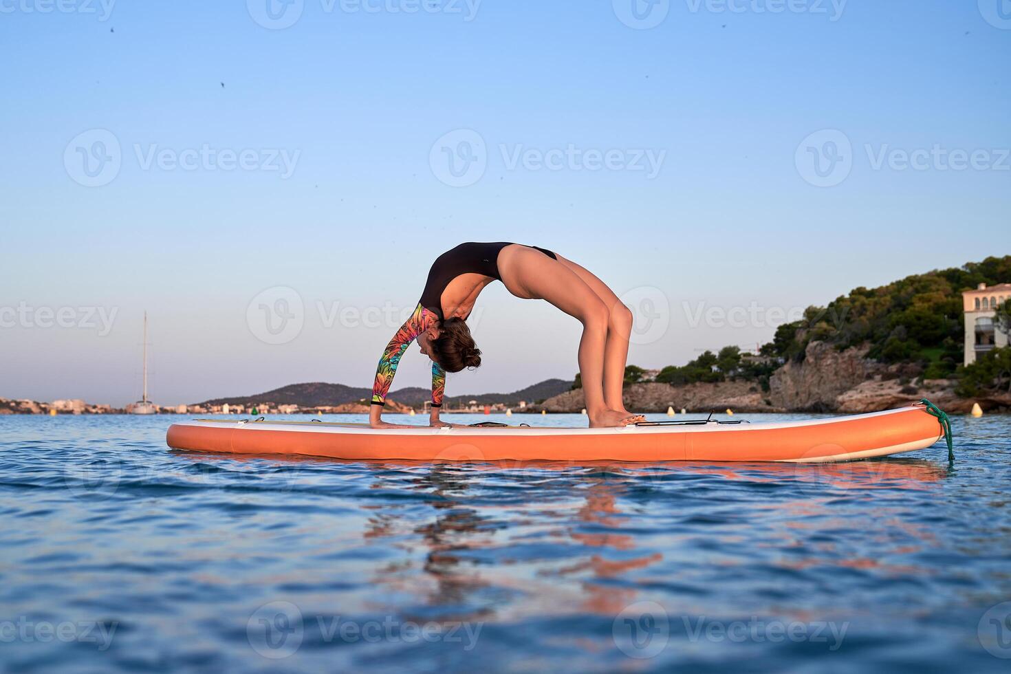 Fit female athlete practicing yoga on paddleboard photo