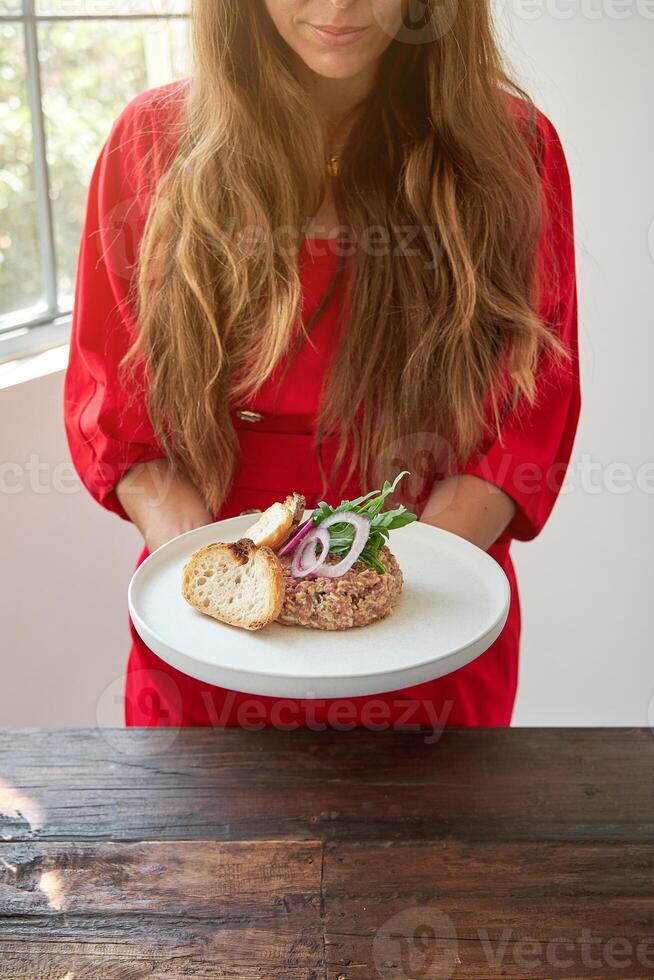 Crop woman with steak tartare on plate photo