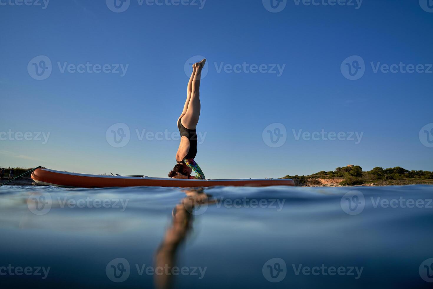 Unrecognizable woman practicing Supported Headstand on SUP board photo