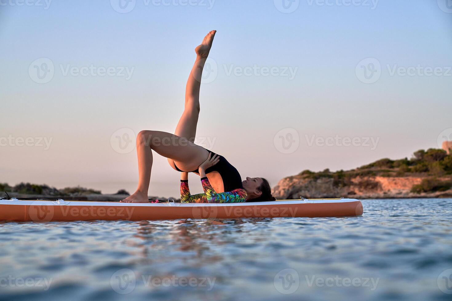 Fit woman taking bridge pose on paddleboard photo