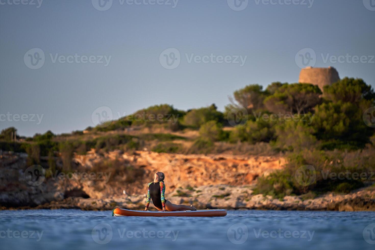 Female athlete taking Cobra pose on paddleboard in sea photo