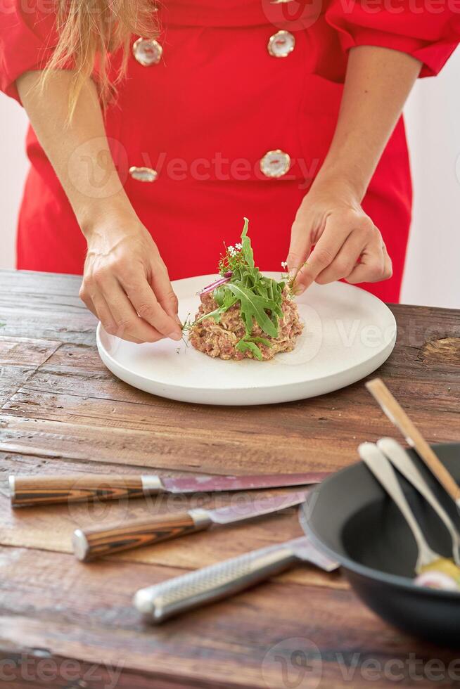 Crop woman with delicious steak tartar in kitchen photo