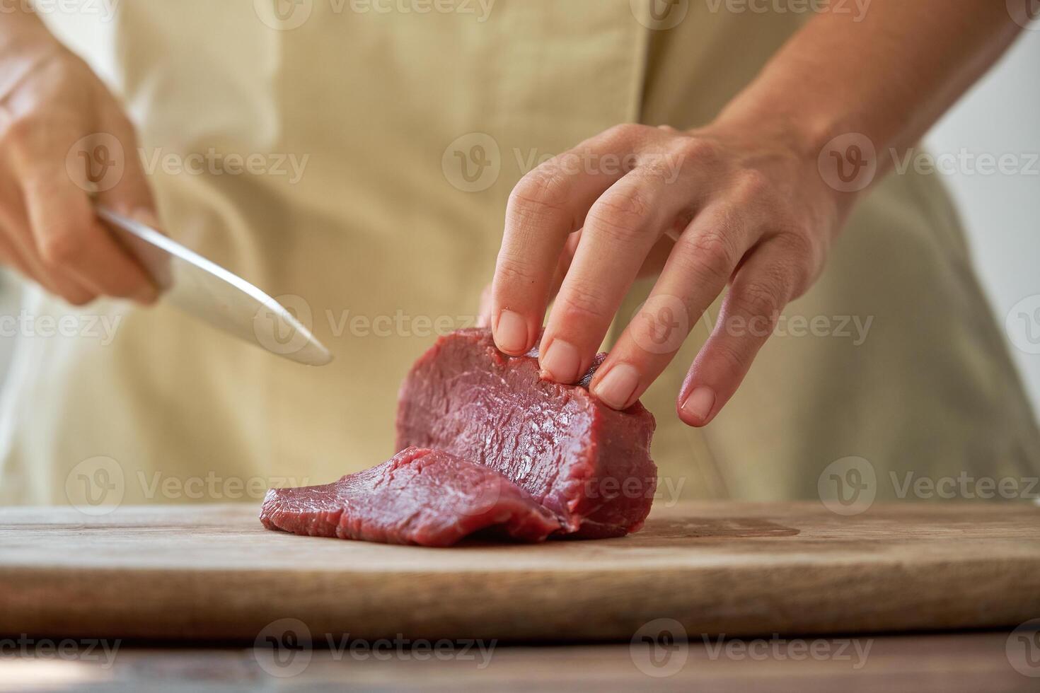 Crop woman cutting beef on board photo