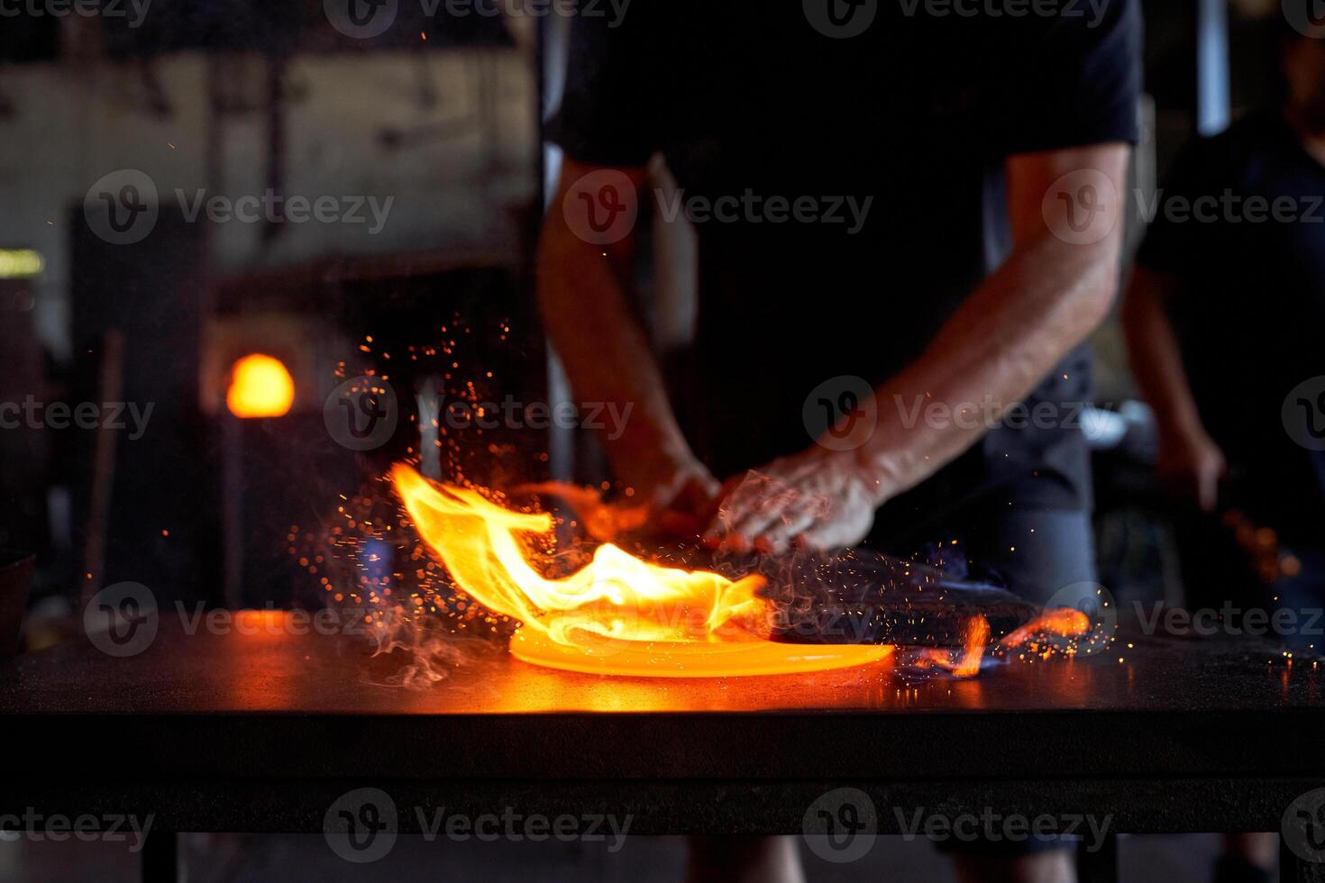 Crop craftsman making glass product in glassblowing workshop photo