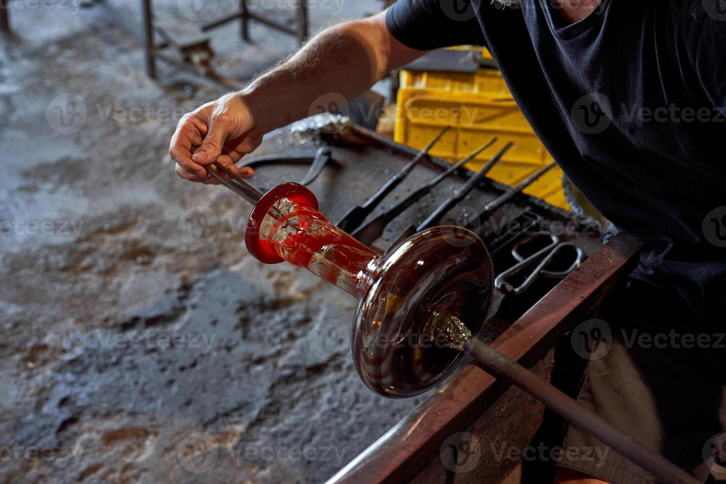 Anonymous worker glassblowing bottle in workshop photo