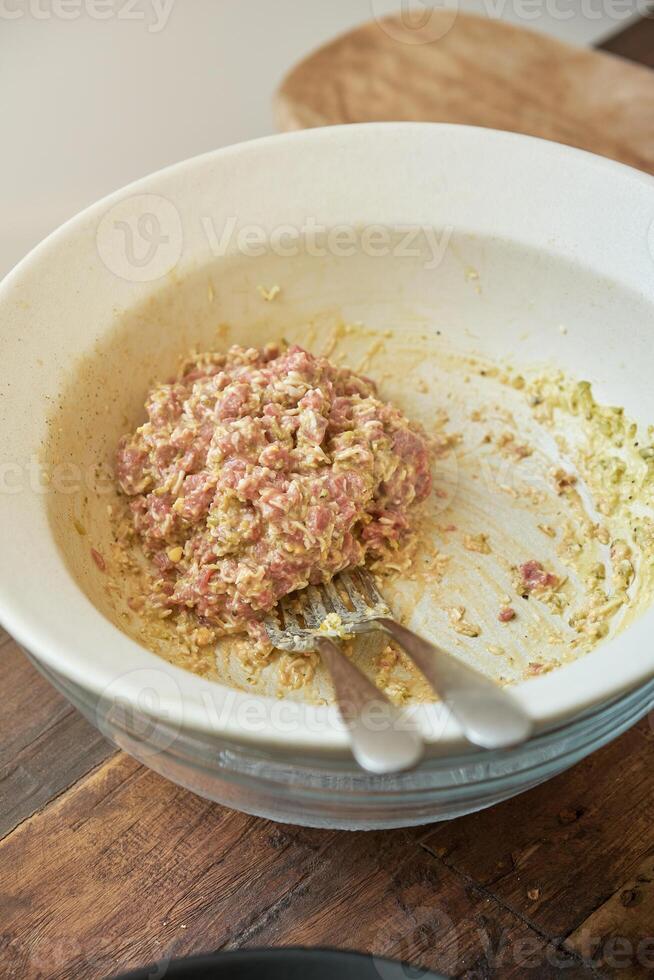 Ceramic bowl with minced raw meat and sauce on wooden table photo