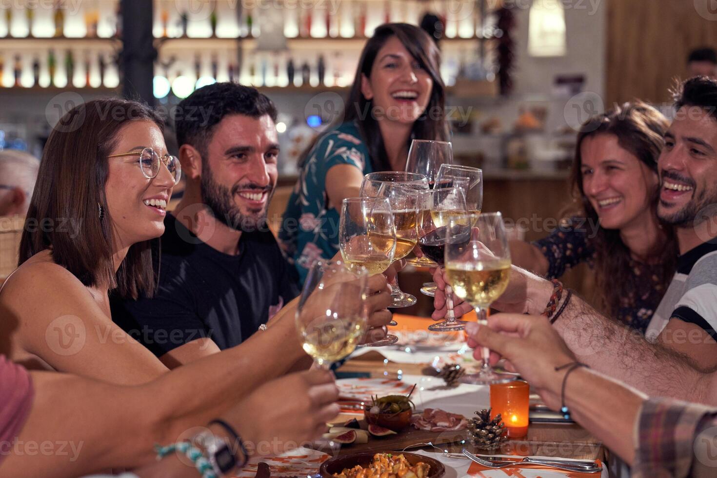 Positive group of friends clinking wineglasses in bar photo