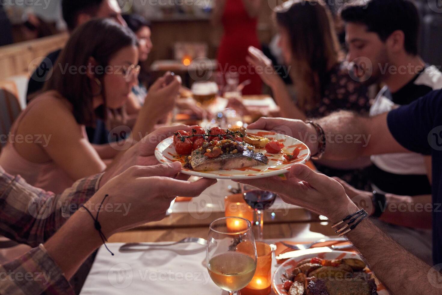 Unrecognizable people passing plate with dish near friends photo