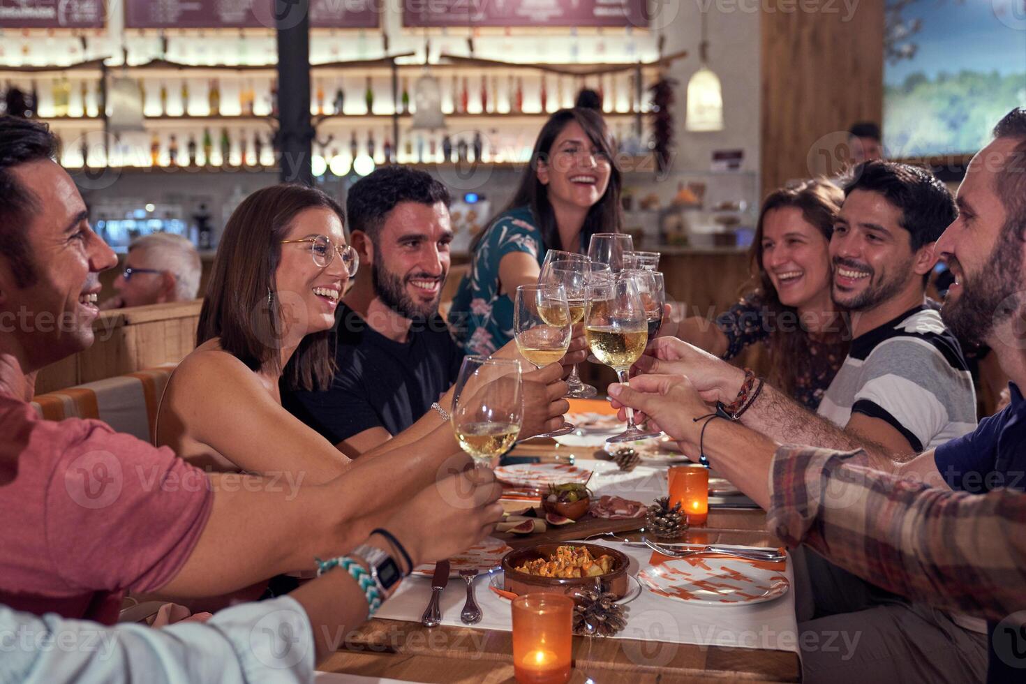 Smiling people gathering in bar and drinking alcohol photo