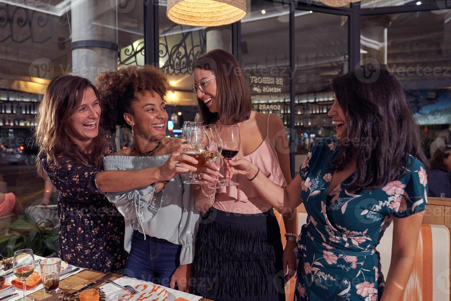 Delighted multiethnic women toasting in restaurant photo