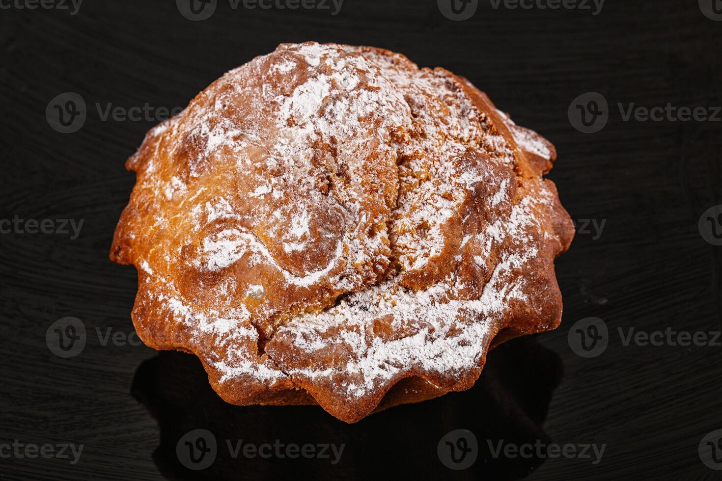 A pastry covered in powdered sugar on a black surface photo