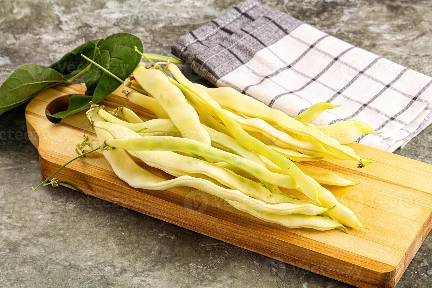 A wooden cutting board with beans and a towel photo