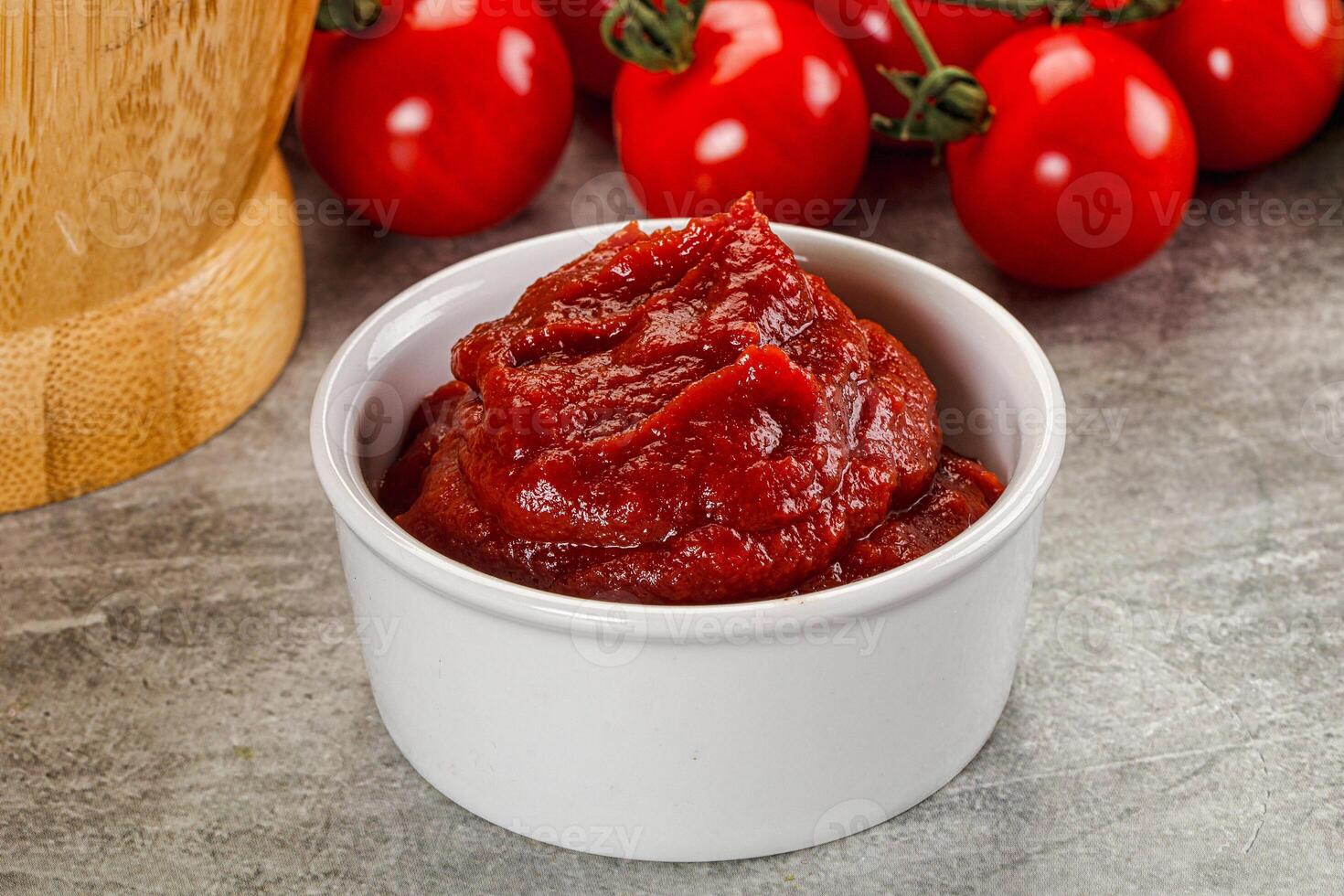 A bowl of tomato sauce next to a wooden chopping board photo