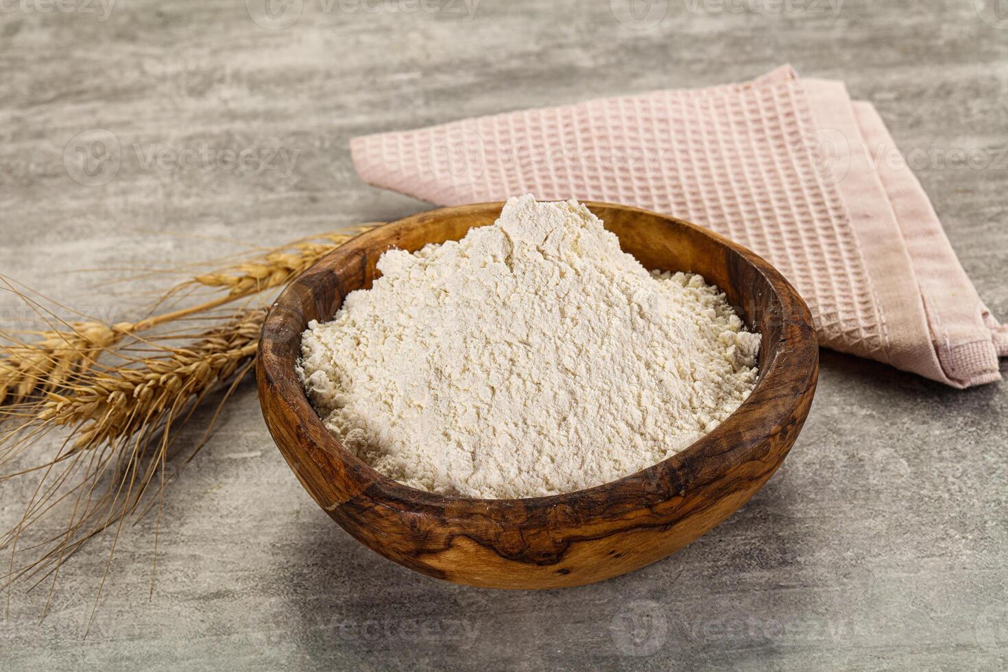 A bowl of flour and a spoon next to a wheat ear photo