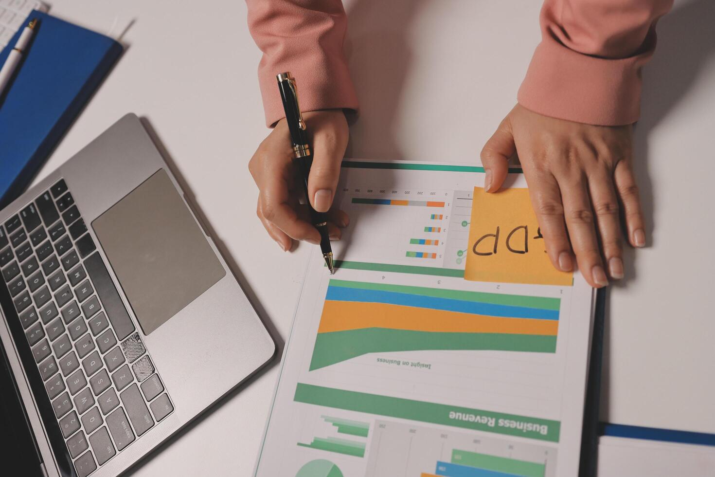 A woman's hands are on a laptop and a paper with graphs photo