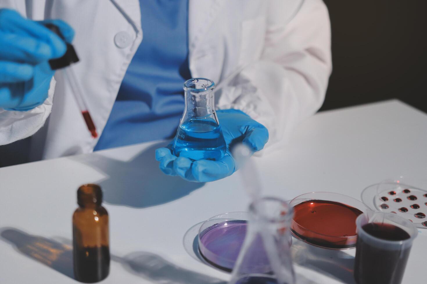 A person in a lab coat holding a test tube photo