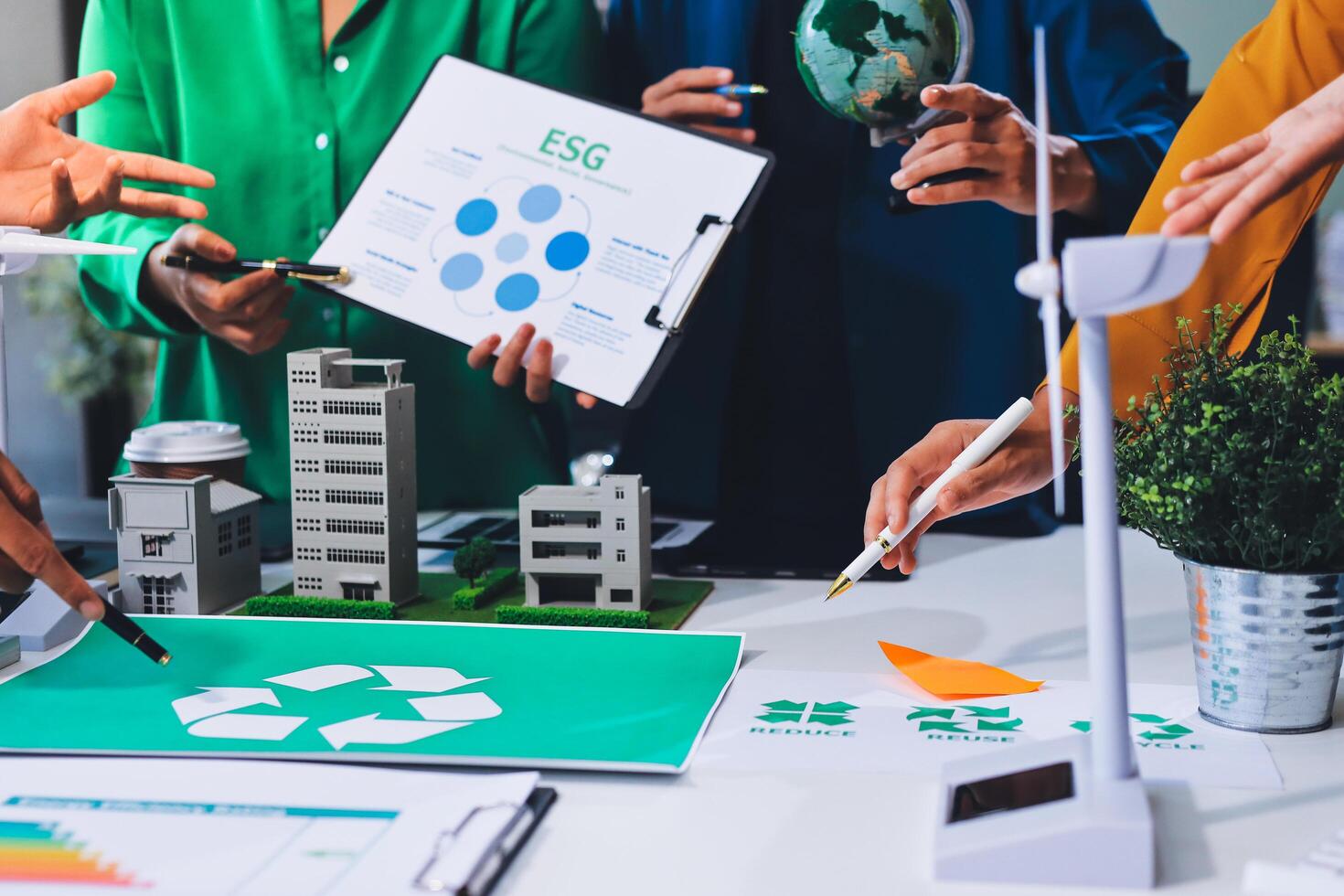 A group of people working on a project with a green recycling sign photo