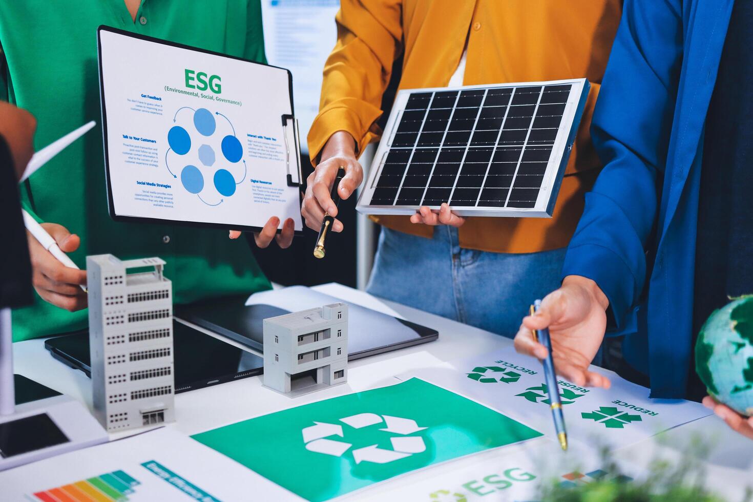 People working on a table with a solar panel and a recycling symbol photo