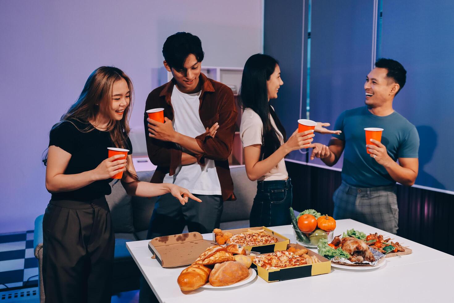 A group of people standing around a table with food photo