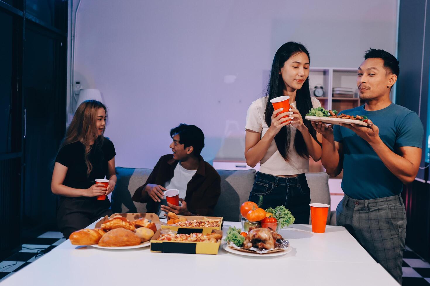 A group of people eating pizza and drinks at a table photo