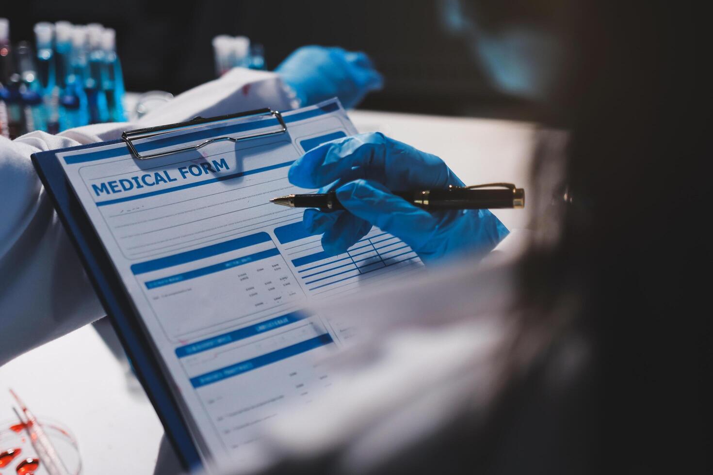 A person in a lab coat is writing on a clipboard photo