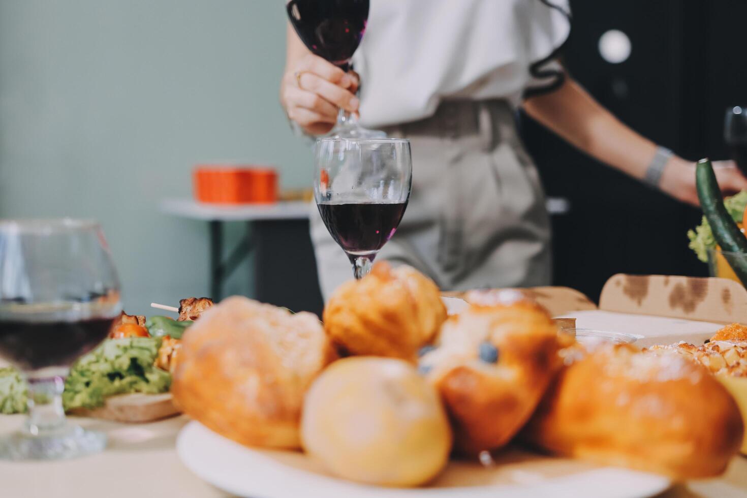 A person holding a glass of wine while sitting at a table with food photo