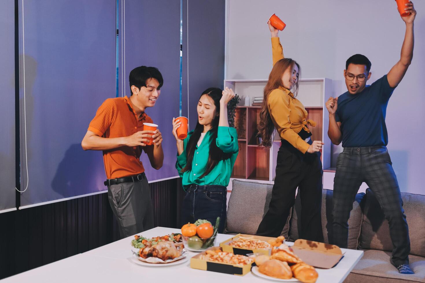 Four people standing around a table with food photo