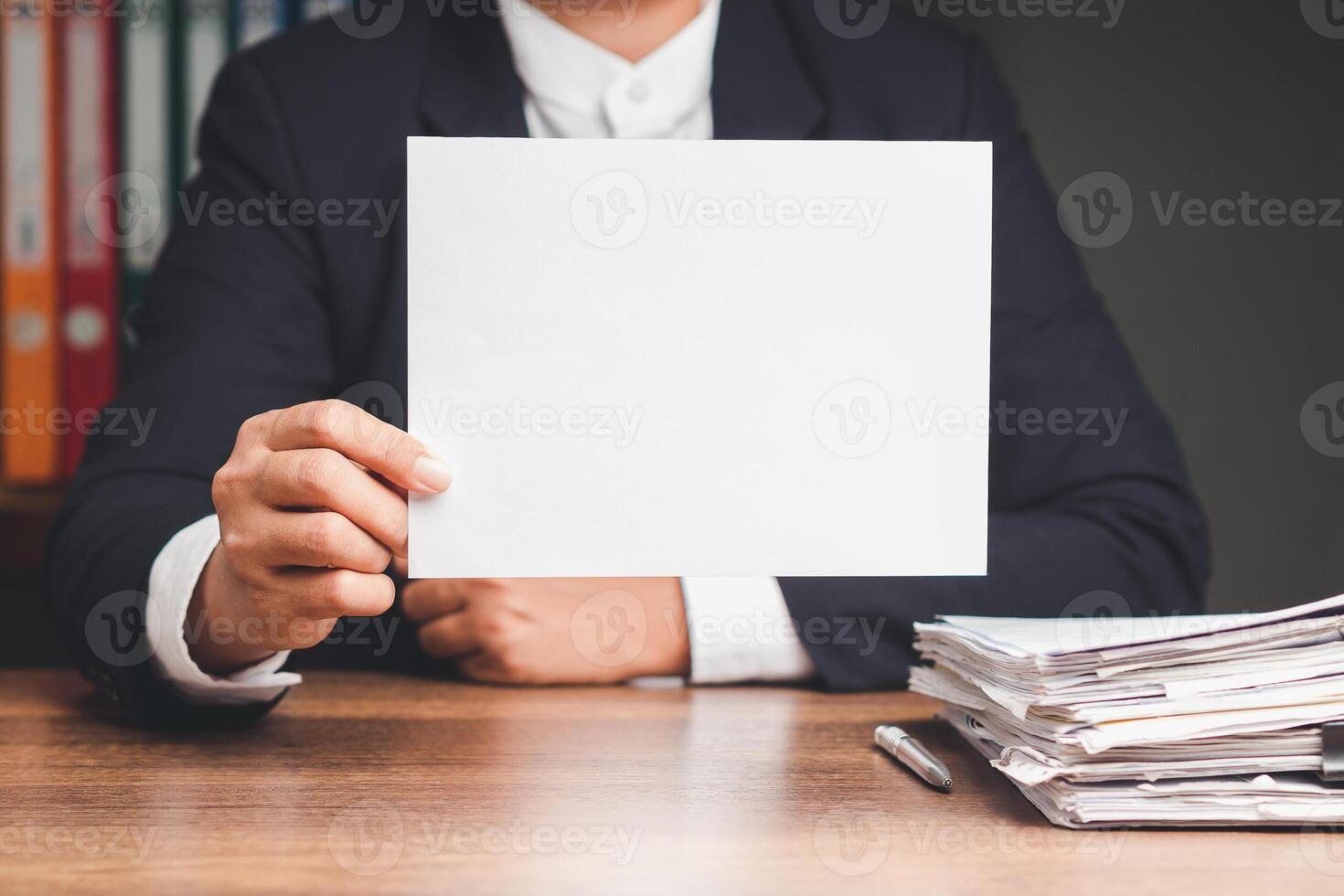 Businessman in a suit holding a blank white paper while sitting at the table photo