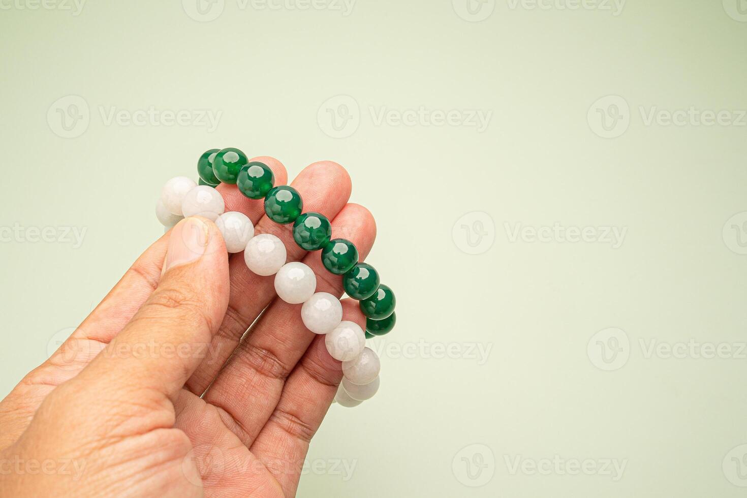 Jade bangles or bracelets in hand against a green background photo