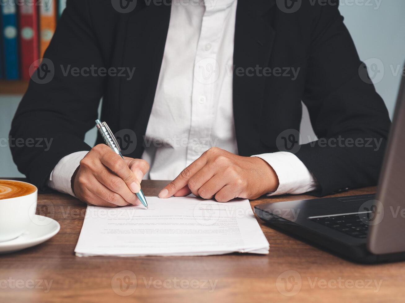 Businessman in a suit signing a lease contract or agreement while sitting at the table. Close-up. photo