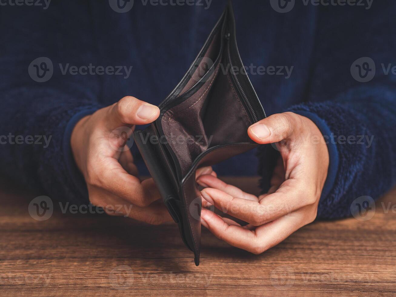 Close-up of hands opens an empty wallet while sitting at the table photo
