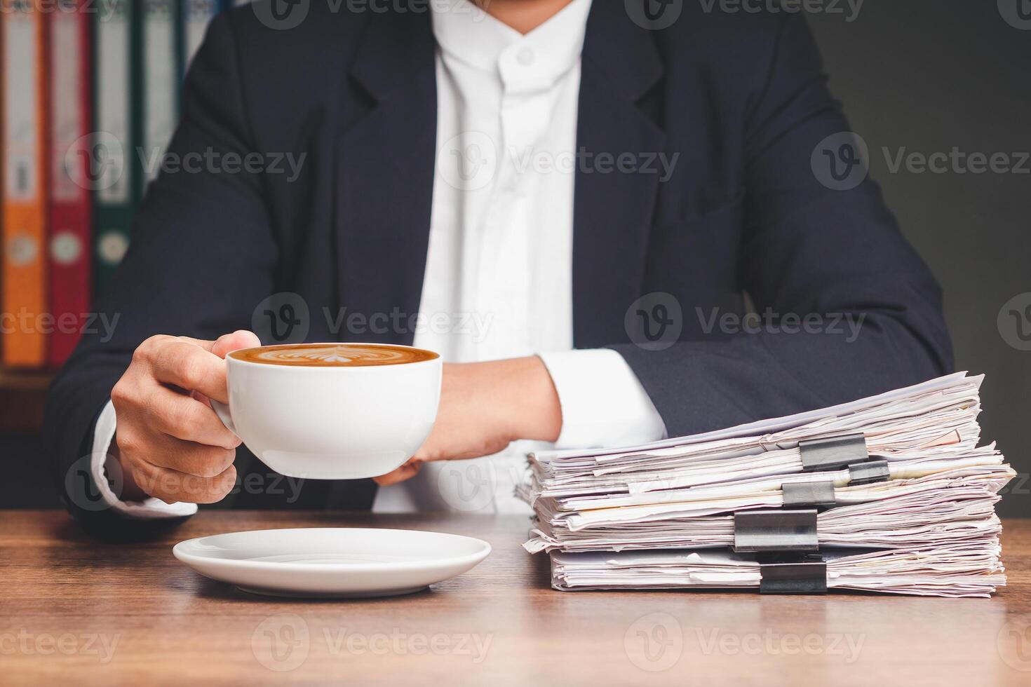 Businessman in a suit hand holding a cup of coffee while sitting working at the table. photo