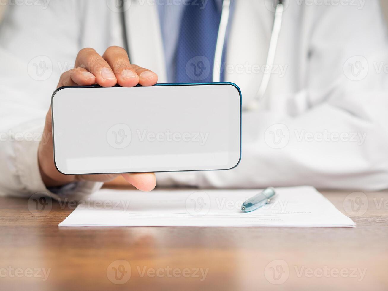 Close-up of doctor is holding a white blank screen smartphone while sitting at the hospital photo