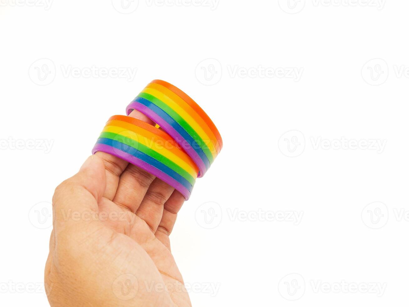 Hand holding of two rainbow wristbands on a white background photo