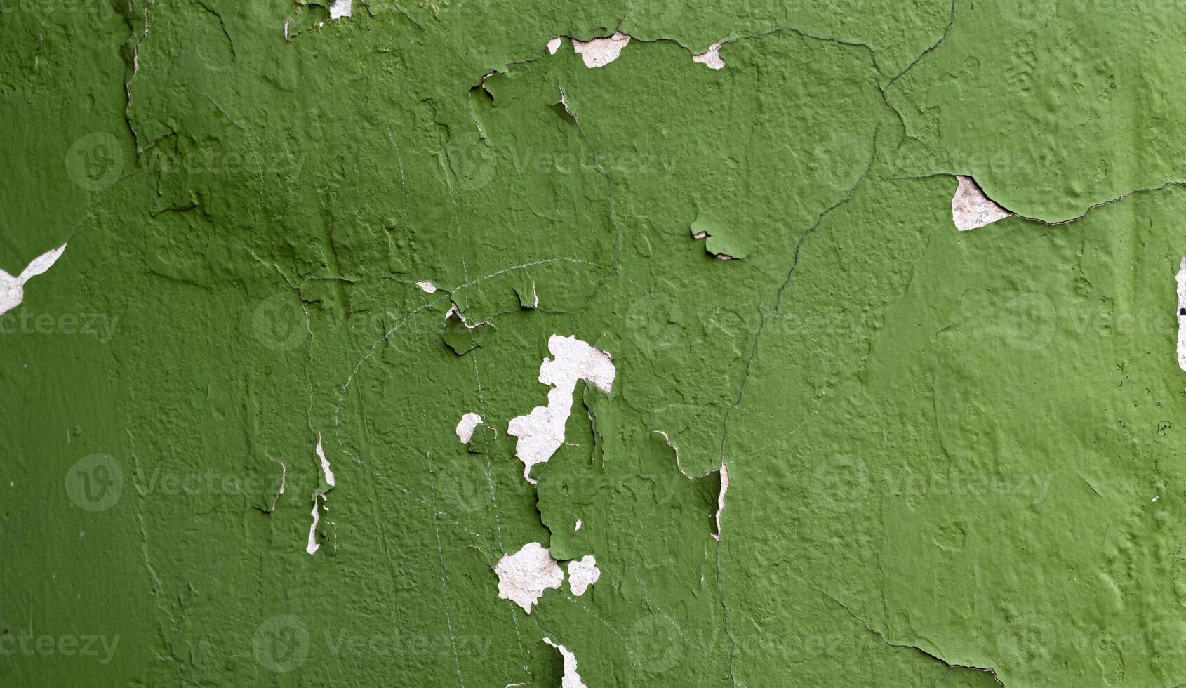 Peeling green paint on a cracked wall surface, showcasing texture and weathered details. Perfect for backgrounds photo