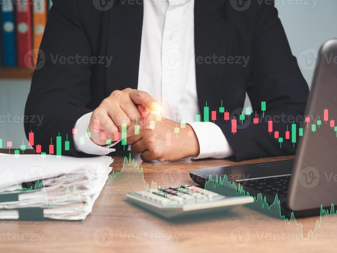Businessman in a suit pointing to graph stock on a virtual screen while sitting at the table photo