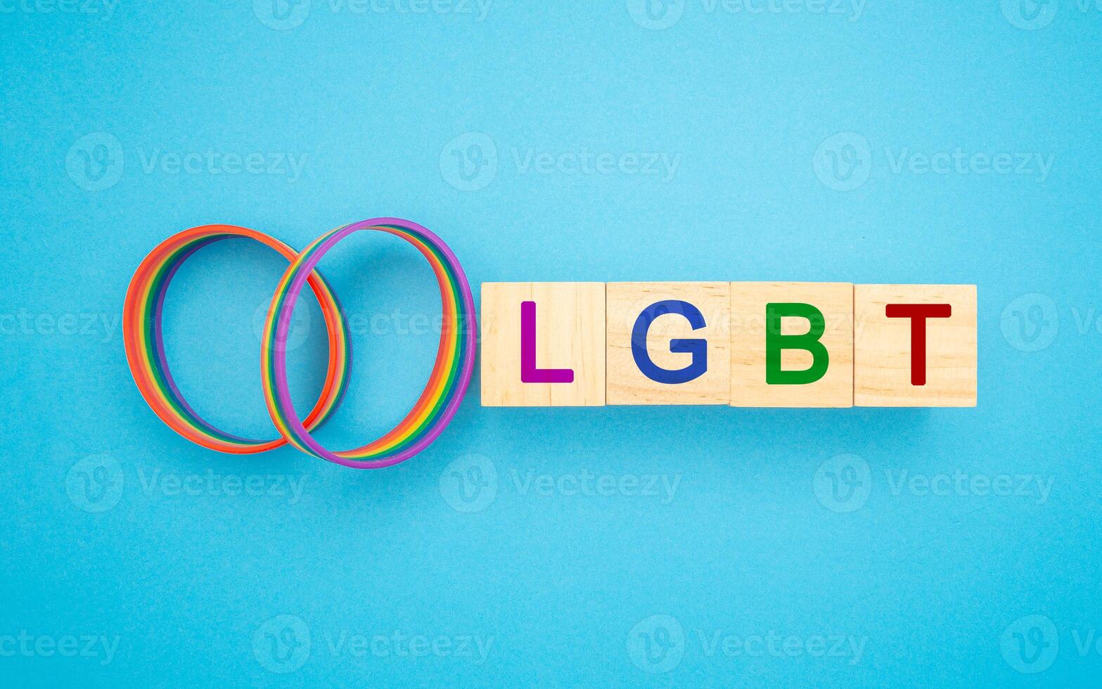 Two rainbow patterned wristbands and wooden cubes with the letters LGBT are on a blue background photo