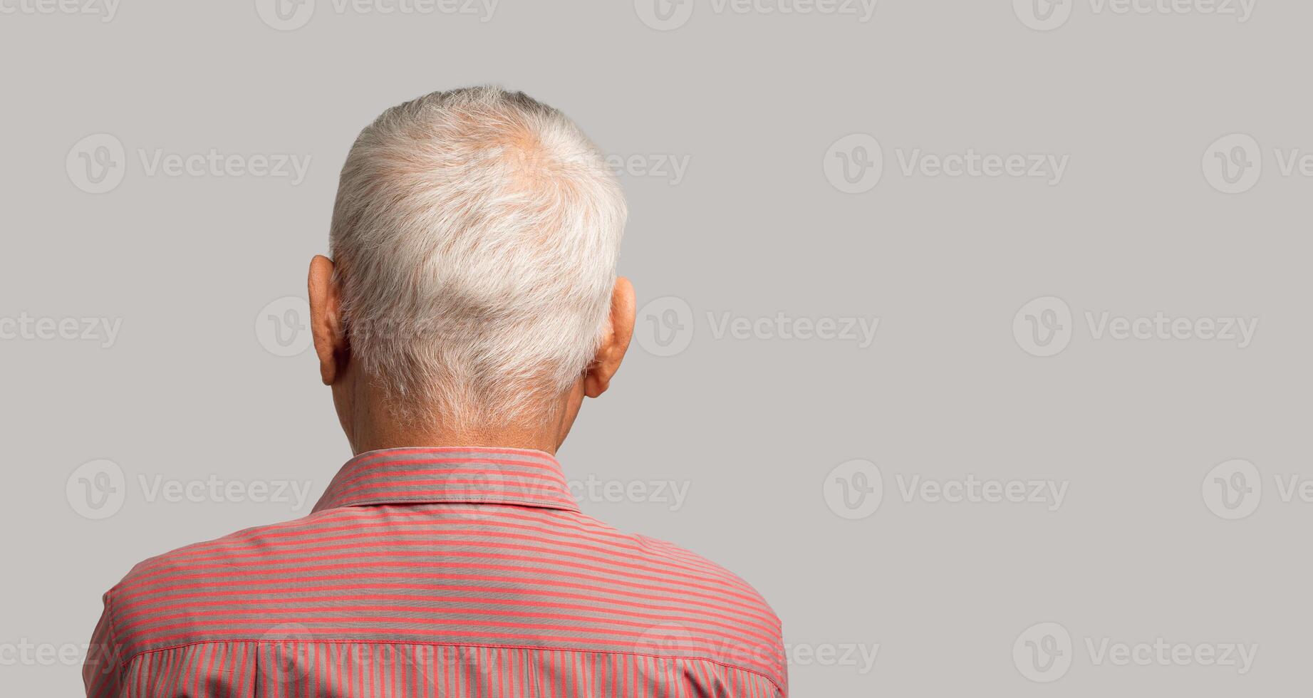 Back view of a senior man with short gray hair while standing on a gray background photo