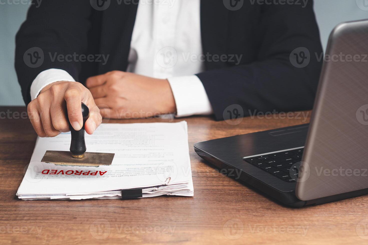 Close-up of businessman in a suit stamped for approved documents while sitting at the table photo