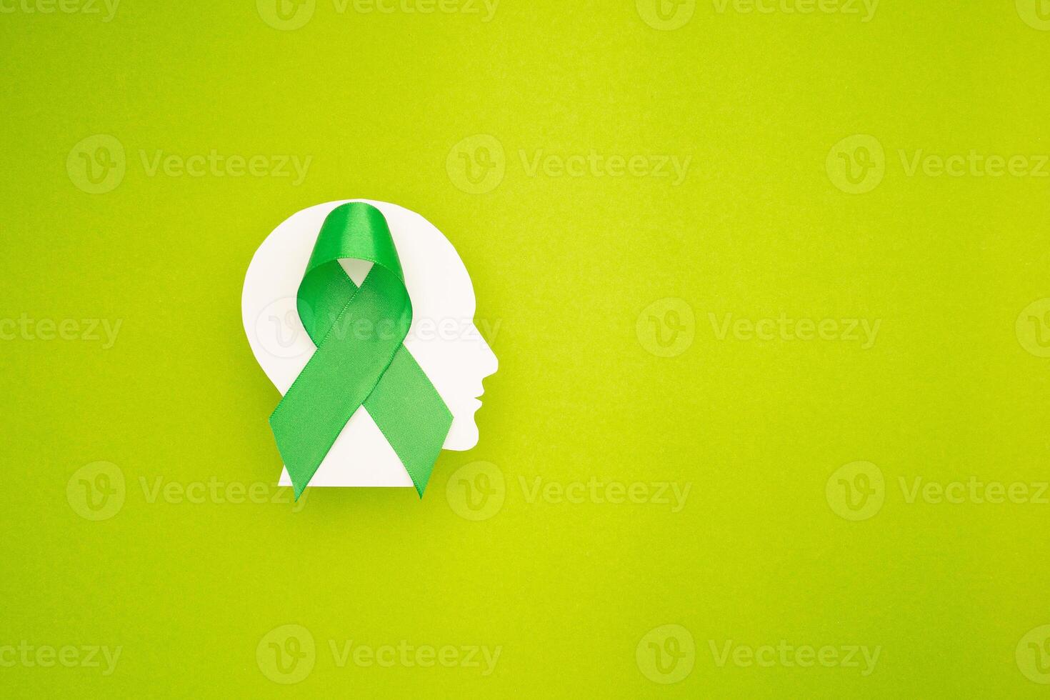A green ribbon on a white brain symbol made from paper on a green background photo