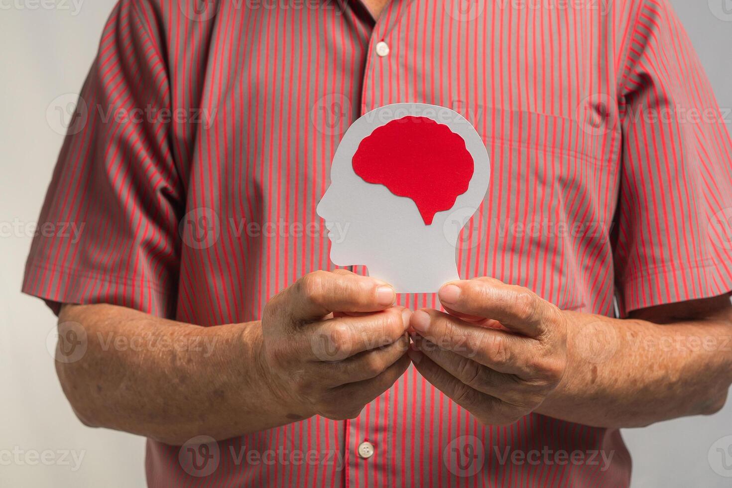 Close-up of hands senior man holding a brain symbol while standing on a gray background photo