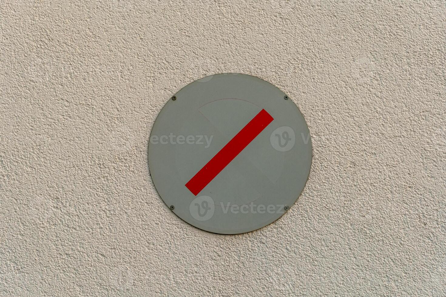 No entry sign displayed on a textured wall indicating restricted access for vehicles and pedestrians photo