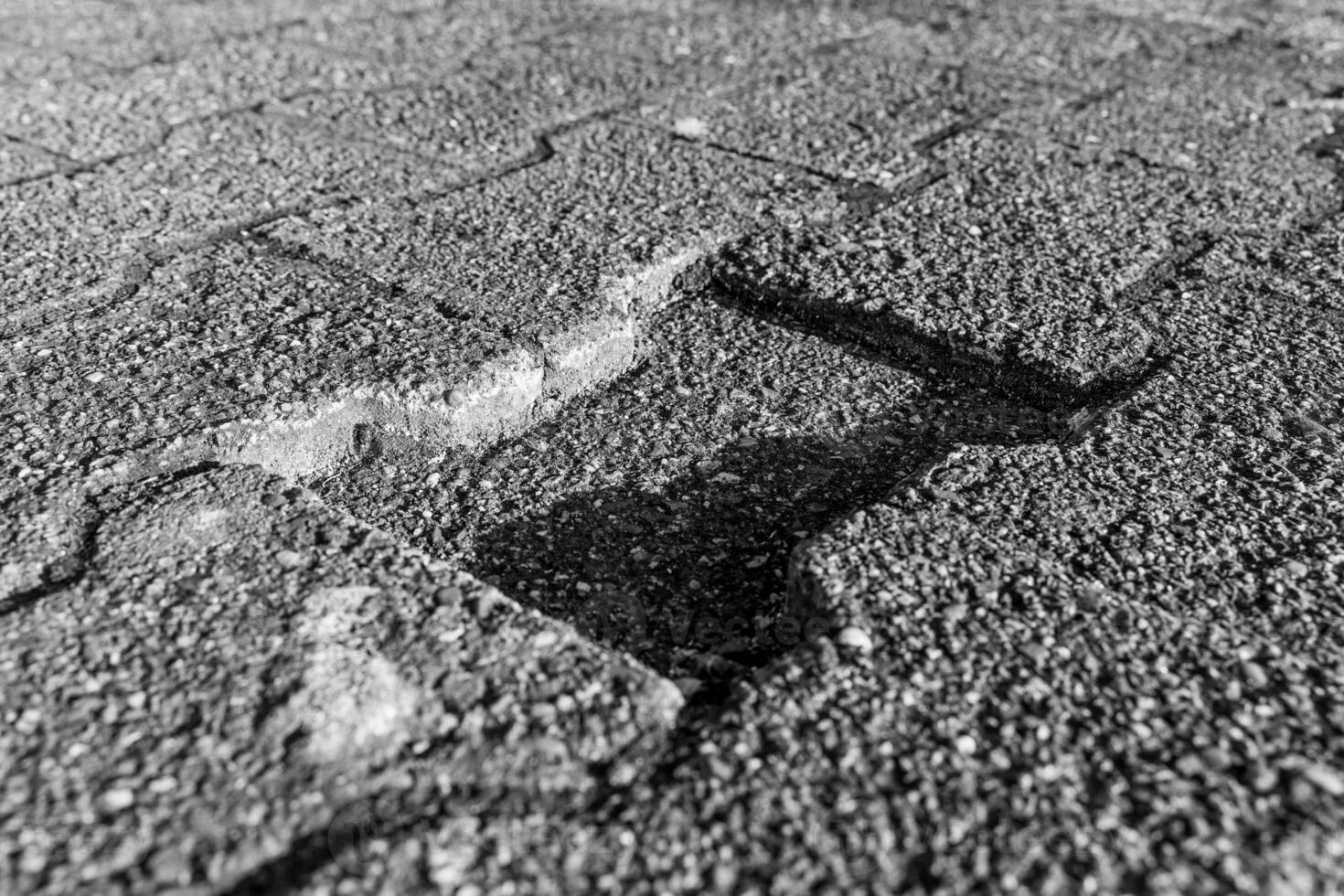 Detailed view of cracked pavement revealing texture and shadows on a sunny day photo